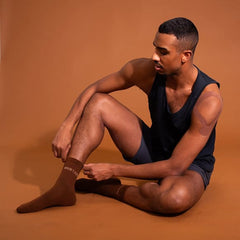 Man sitting on a brown background wearing dark socks with text