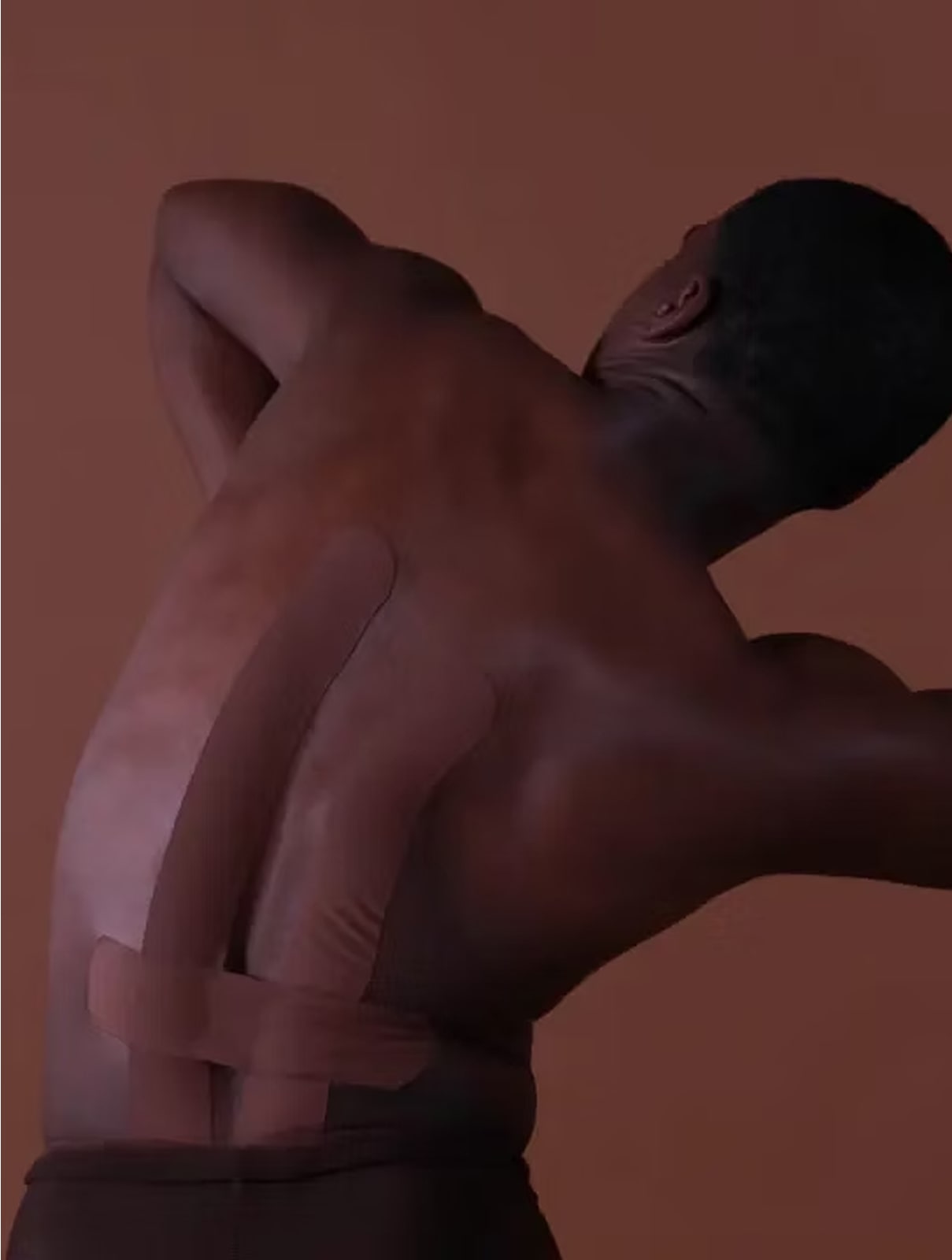 Person with kinesio tape on their back against a brown background