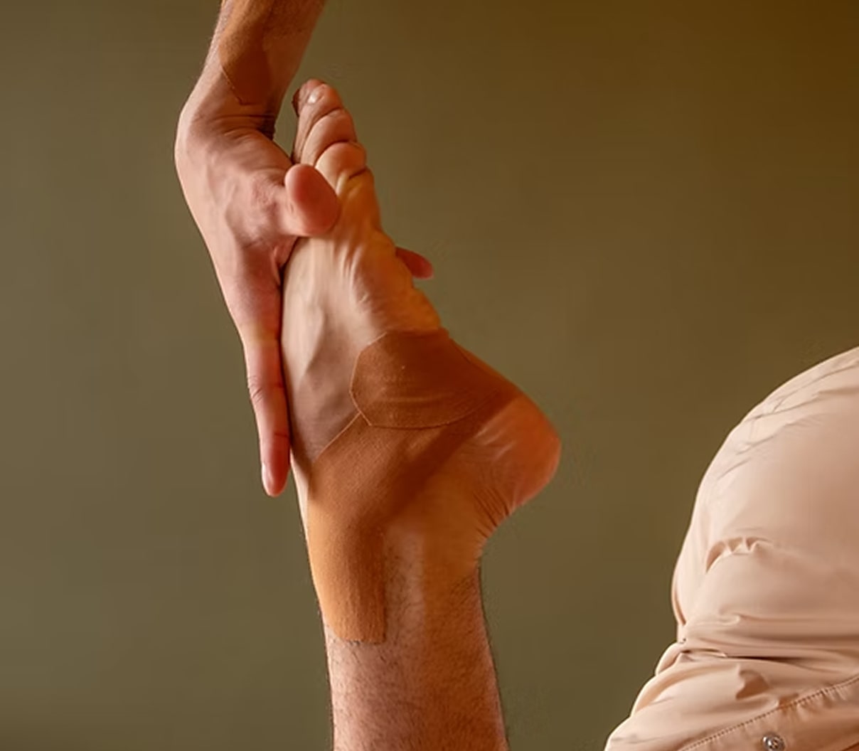Person wearing a beige ballet slipper with a plain background