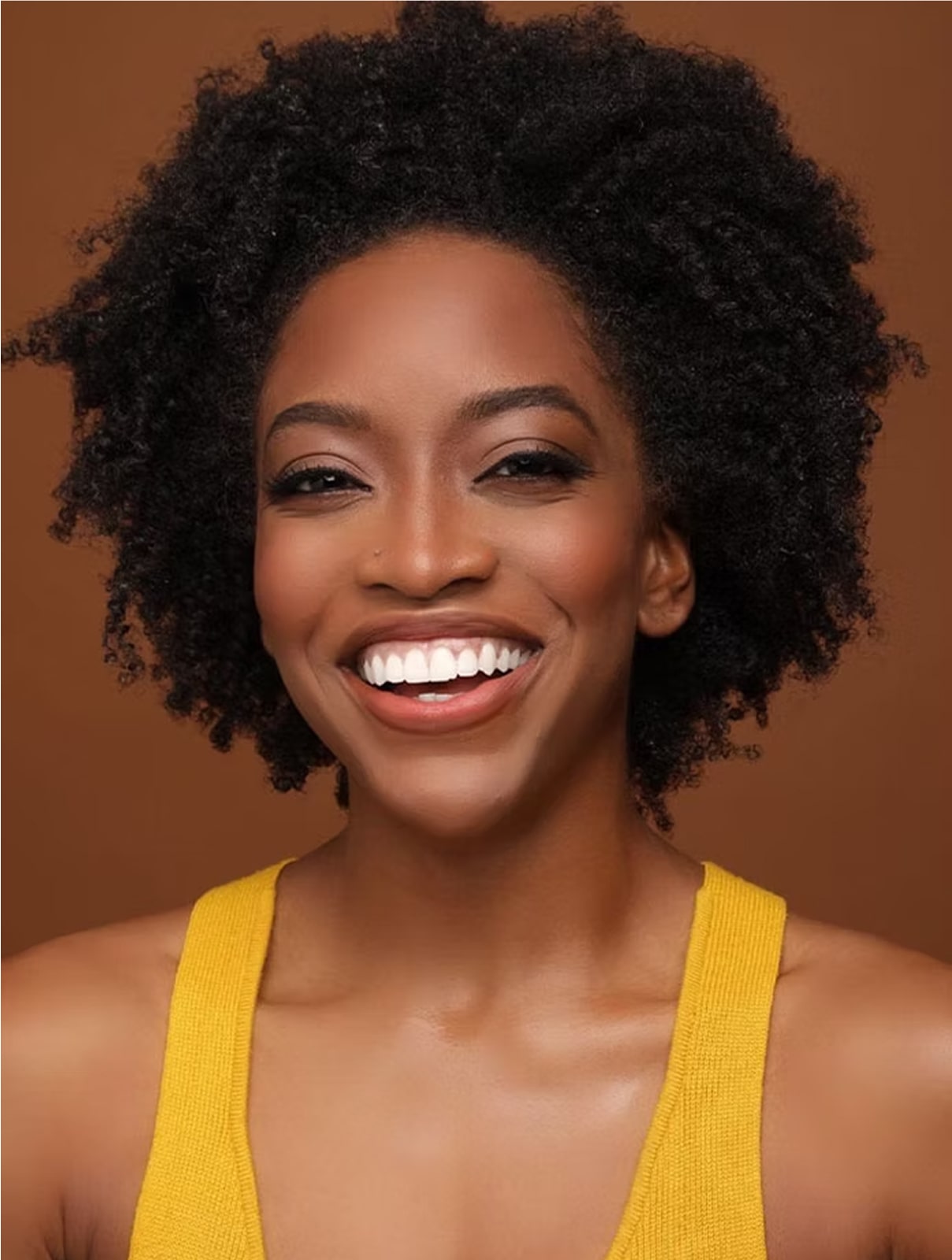 Tamisha, Huetape's founder, with a big smile wearing a yellow tank top against a brown background