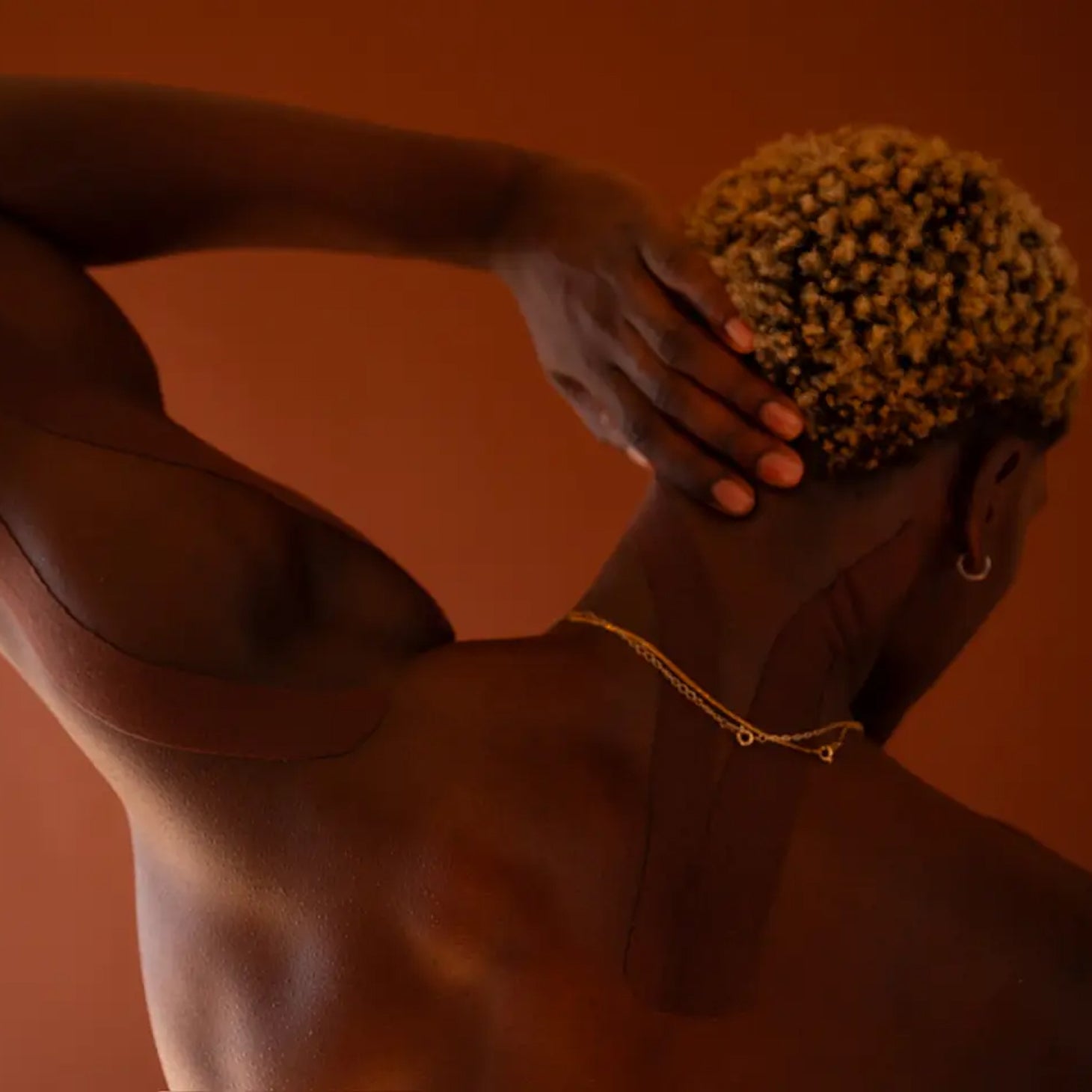 Person with textured hair against a warm brown background