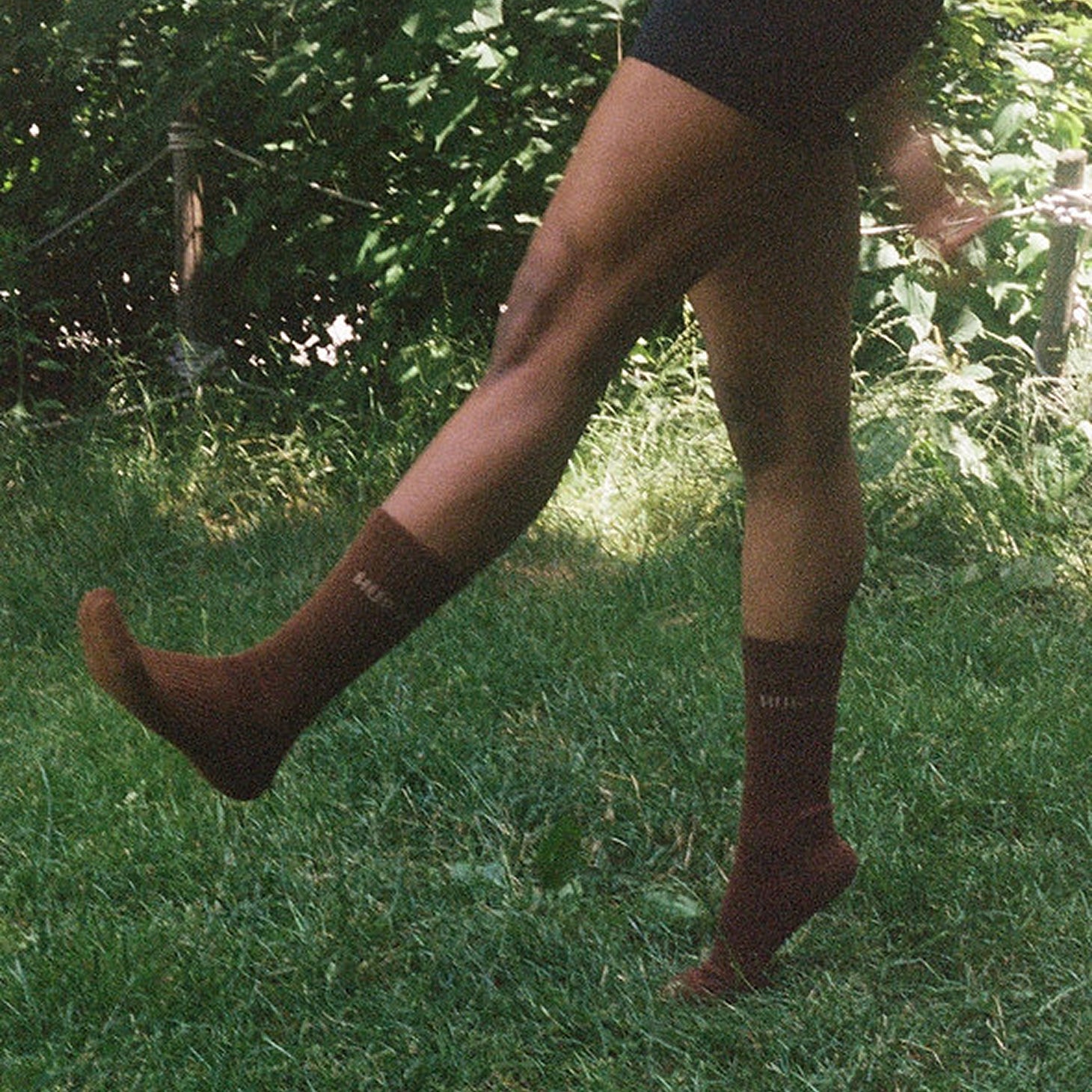 Person wearing brown knee-high socks running on grass with a blurred background