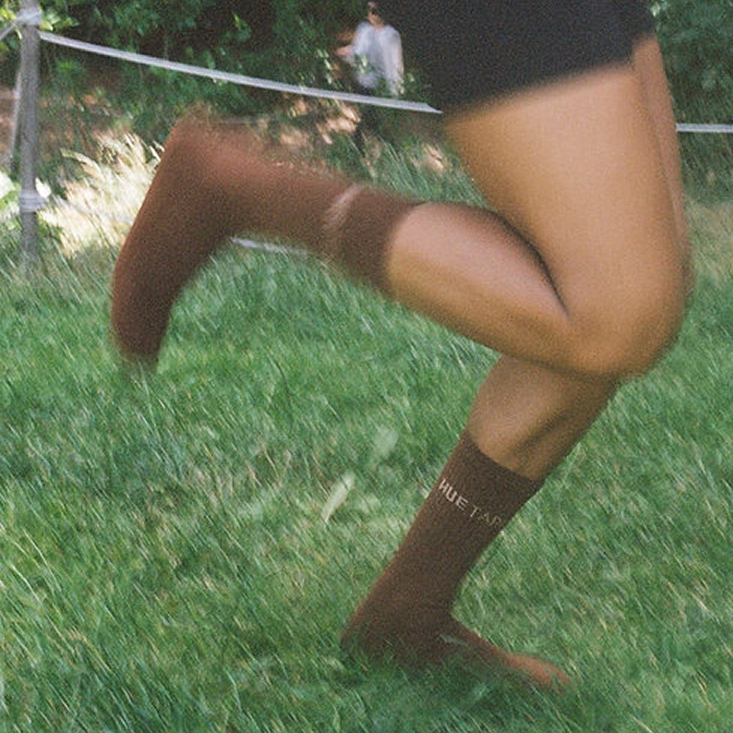 Person wearing brown knee-high socks with a visible brand logo on grass.