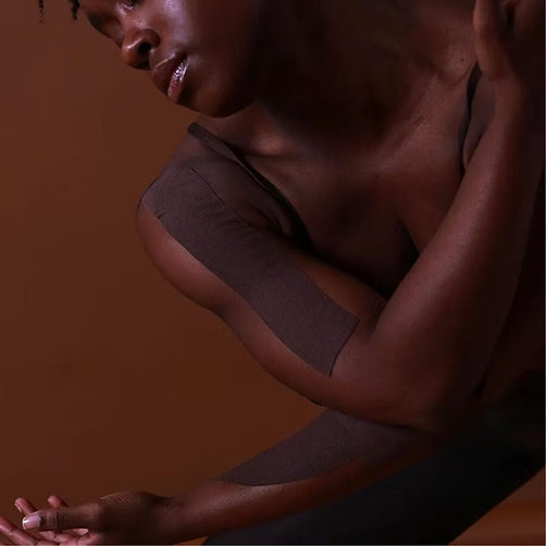 Person with dark kinesio tape set against a matching background