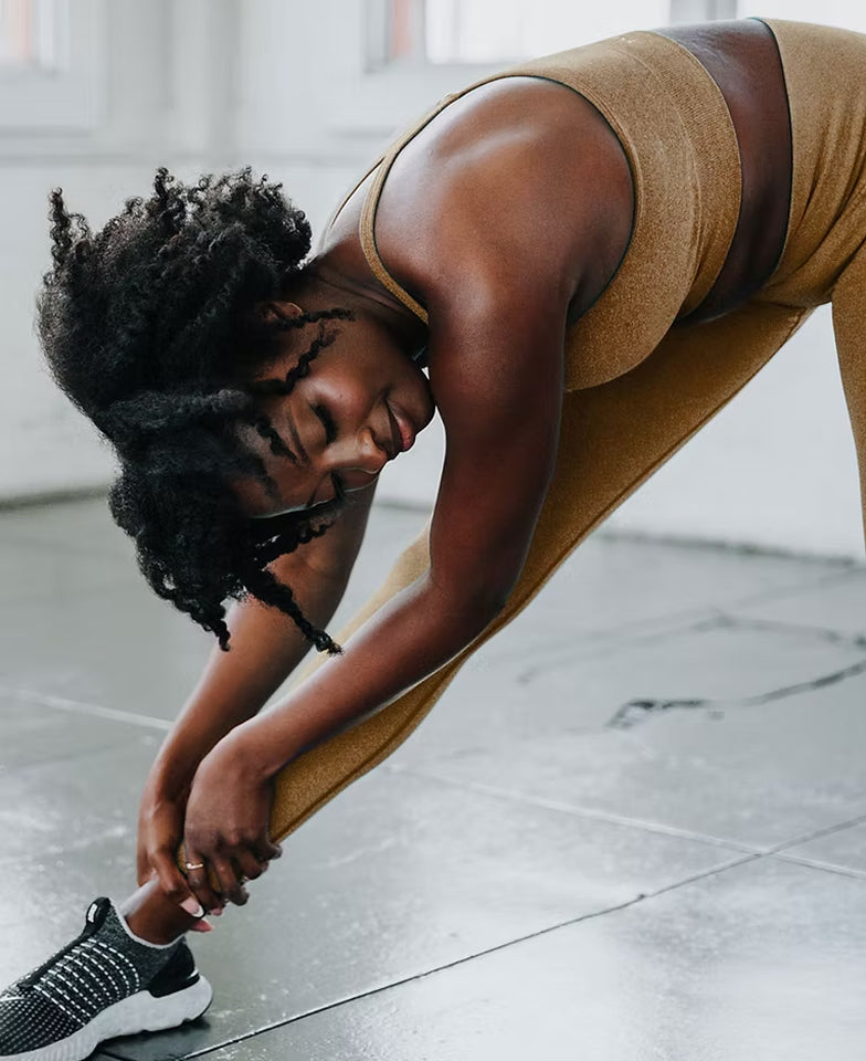 Person in athletic wear stretching on a tiled floor