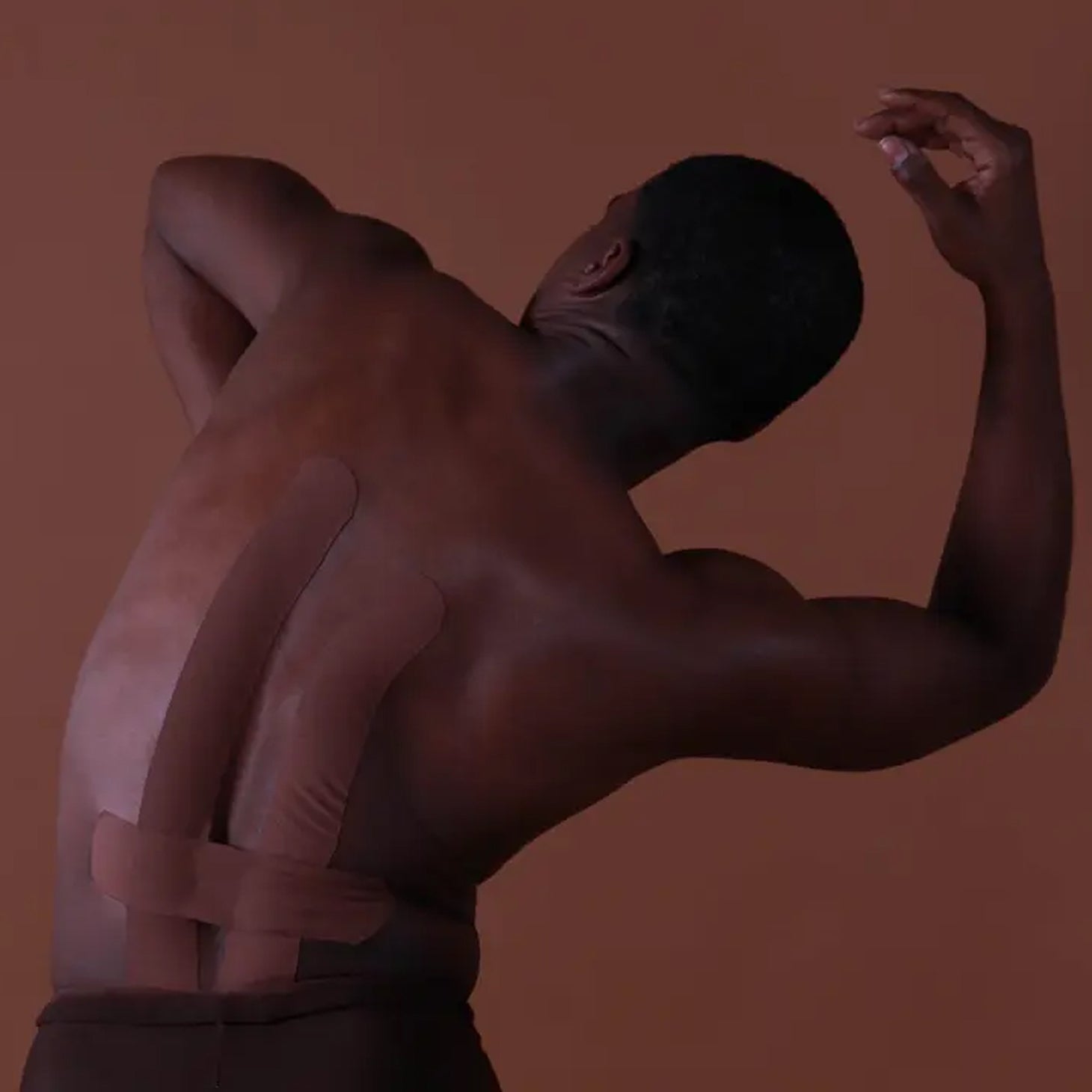 Man with a bandage on his back against a brown background