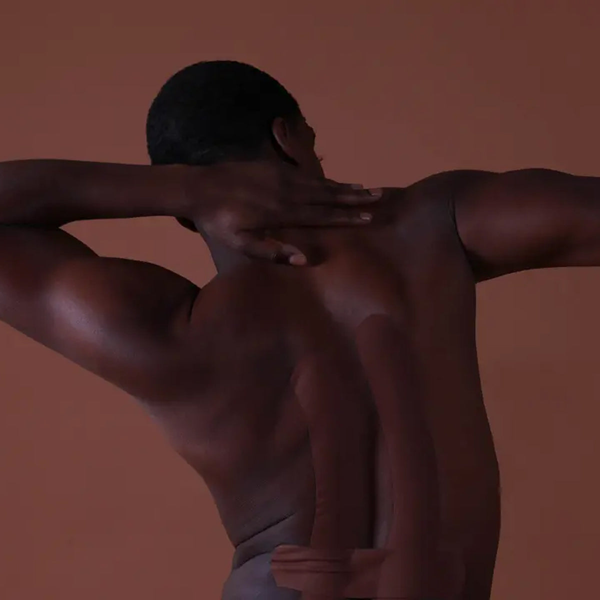 Man with a muscular build against a brown background