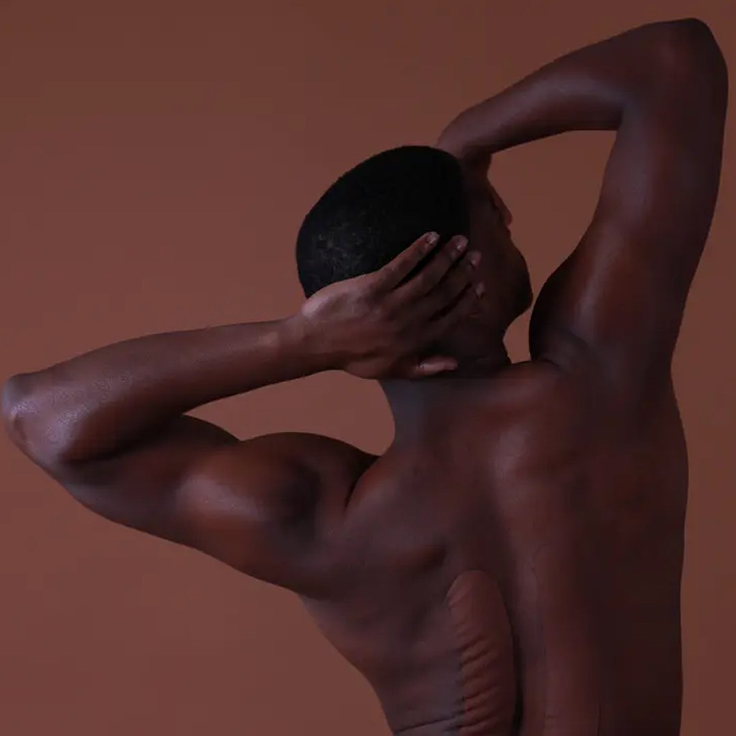 Man holding a black sphere against a brown background