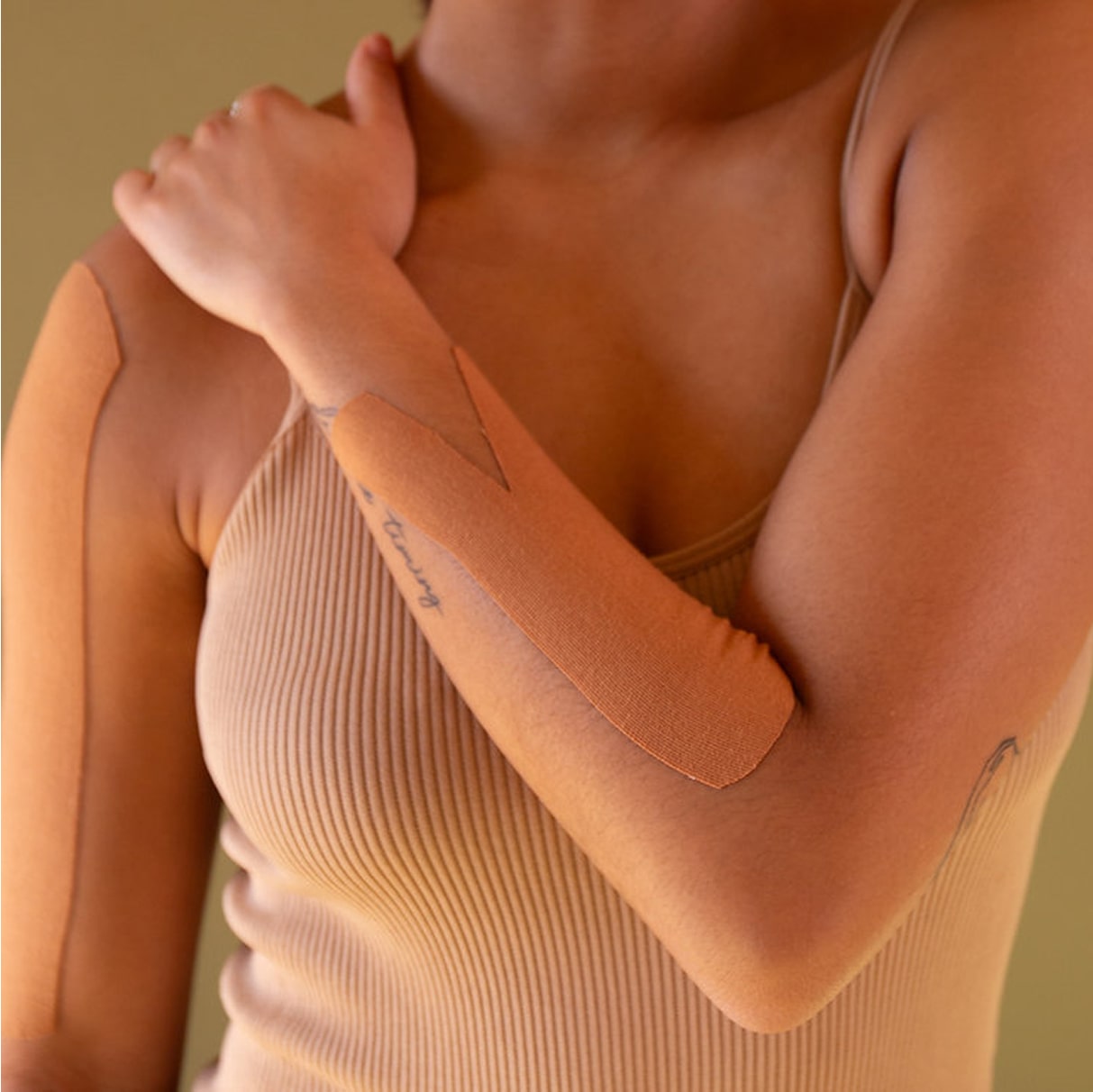 Close-up of a person wearing a beige tank top against a green background